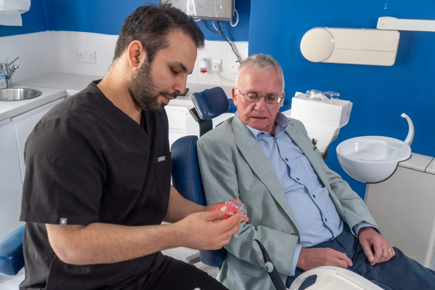 A clinician showing an implant-retained denture to a patient in the treatment chair